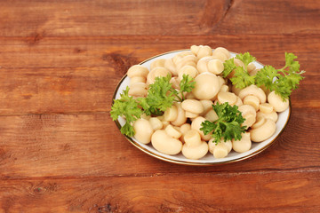 Marinated mushrooms in saucer on wooden table