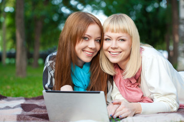 two sisters with laptop in the park