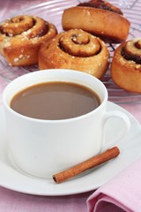 A cup of coffee with fresh cinnamon rolls