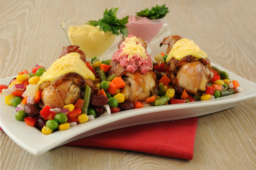 Chicken leg wrapped in bacon with vegetables and different sauce