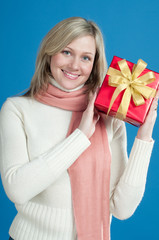 Happy blond woman in white wooly holding gift box