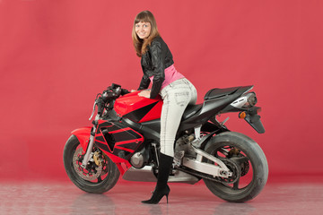 Fototapeta na wymiar Young girl with a bike, on a red background