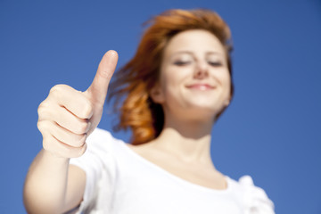 Portrait of red-haired girl in white which show hand V symbol.