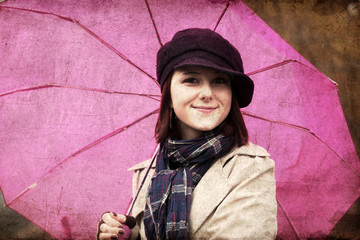 Girl in cloak and scarf with umbrella at park in rainy day. Phot