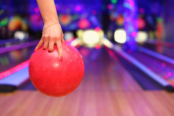 Female hand holding ball before throwing in bowling club - obrazy, fototapety, plakaty