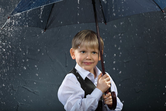 smiling boy dressed in white shirt standing under umbrella