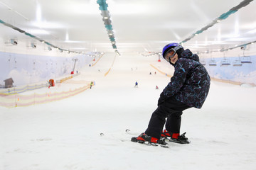 Happy child dressed in sports clothes and helmet and ski goggles