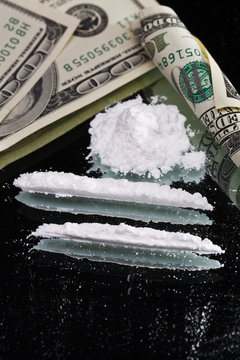 Cocaine drugs heap still life on a mirror with rolled 100 dollar