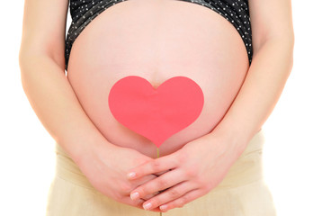 closeup of a pregnant woman holding red heart