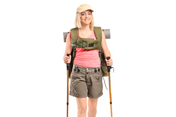 A smiling woman with backpack and hiking poles posing