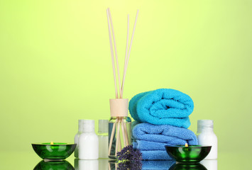 Obraz na płótnie Canvas Bottle of air freshener, lavander and towels on green background