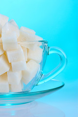 refined sugar in glass cup on blue background