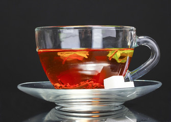 black tea, mint and sugar in cup on black background