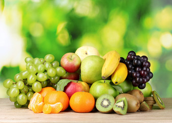 Ripe juicy fruits on wooden table on green background