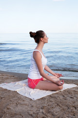 Fototapeta na wymiar Young beautiful woman doing yoga near the sea alone