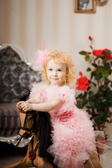 Child in a pink dress on a toy horse