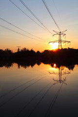 Fototapeta na wymiar Pylon energii elektrycznej z odbicia w wodzie o zachodzie słońca