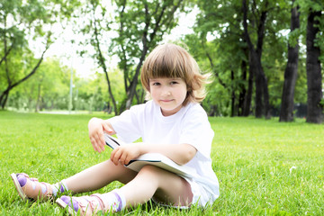 Fototapeta na wymiar Portrait of little girl reading a book in the park