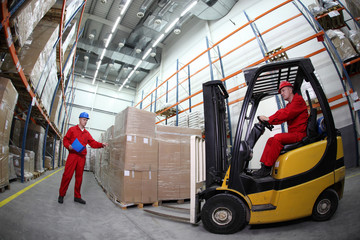 two workers  loading pallets  with  forklift truck