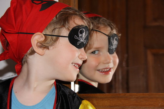 Ein Kind in Verkleidung als Pirat betrachtet sich zufrieden und glücklich im Spiegel