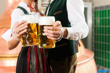 Man and woman with beer glass in brewery