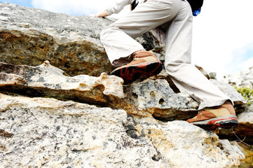 Feet with hiking boots climbing a rocky wall