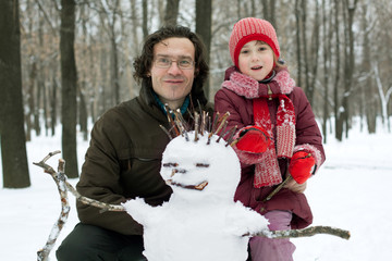 Dad and daughter next to the snowman