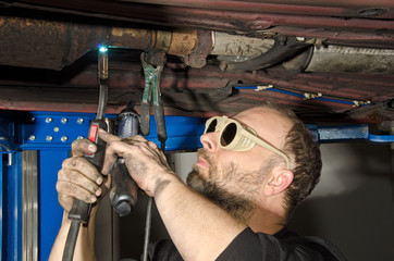 KFZ-Werkstatt: Reparaturarbeiten am Boden eines PKW