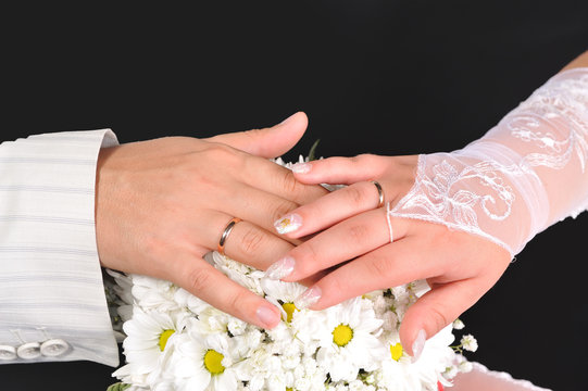 Bride and groom hands with bouquet