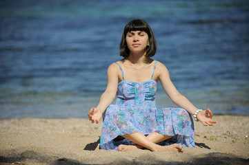 Fototapeta na wymiar Meditating young woman by the sea