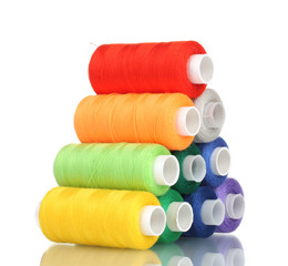 Pyramid of many-coloured bobbins of thread isolated on white