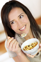 Beautiful brunette eating cereals in the morning