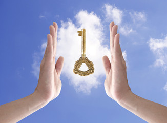 Plakat the key to success (hand holding key against blue sky)