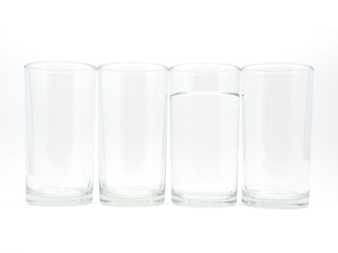Four glasses with water in one glass on white background