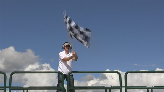 Man waving a checkered flag on a raceway