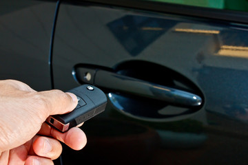 a hand holding a remote control pointing to a car