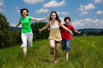 Active family - mother and kids running, jumping outdoor