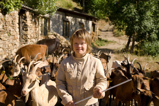 A herd of goats following a girl with Down syndrome