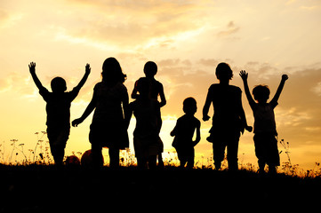 Silhouette, group of happy children playing on meadow