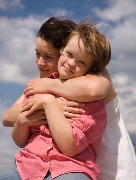 A girl embracing her sister with Down syndrome.