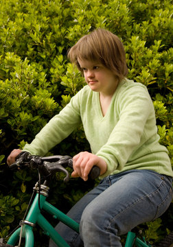 A girl with Down syndrome riding her bicycle.
