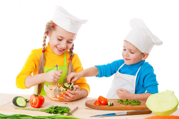 Two smiling kids mixing salad