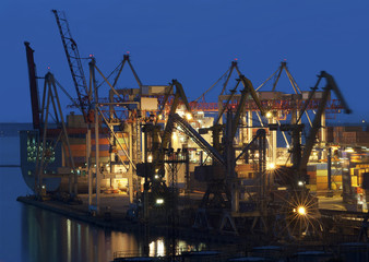 Fototapeta na wymiar cranes at the container port terminal in sunset time