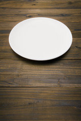 木のテーブルに白色の丸皿のアップ