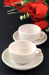 Tazzine di caffè e rose su sfondo nero
