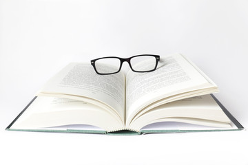 Libro aperto con occhiali su fondo bianco