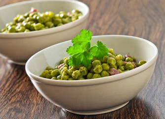 Peas with bacon in terracotta bowl.