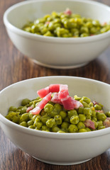 Peas with bacon in terracotta bowl.