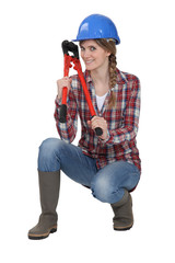 Woman holding bolt cutter whilst in crouching position