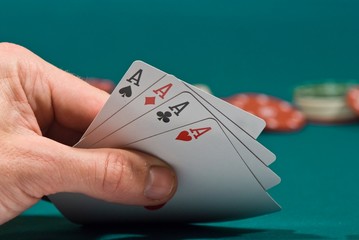 playing cards in a hand on a green felt